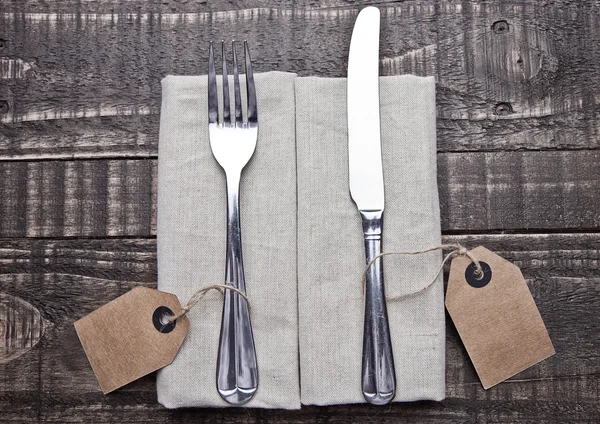 Knife and fork inside kitchen towel on wood board