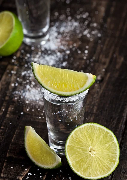 Tequila Silver Shot mit Limettenscheiben und Salz auf Holzbrett — Stockfoto