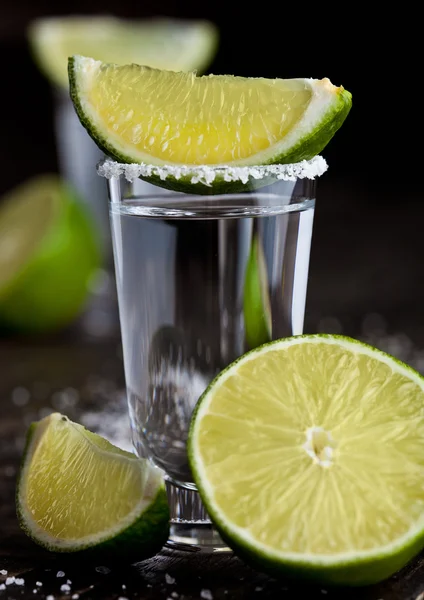 Tequila colpo d'argento con fette di lime e sale su tavola di legno — Foto Stock