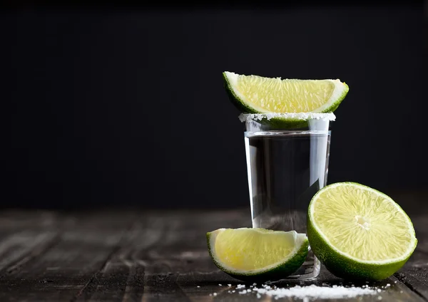 Tequila colpo d'argento con fette di lime e sale su tavola di legno — Foto Stock