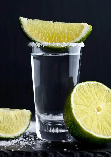 Tequila Silver Shot mit Limettenscheiben und Salz auf Holzbrett — Stockfoto