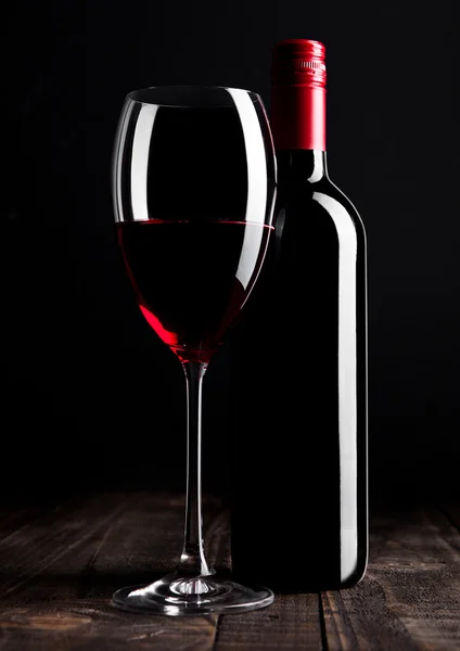 Bottiglia di vino rosso e vetro su tavolo di legno nero — Foto Stock