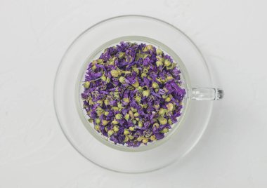 Mavi mallow çiçekli çay, beyaz arka planda cam bardakta. Üst görünüm