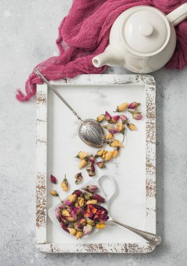 Gül tomurcukları çayları ahşap kutuda karıştırır çay süzgeç infüzyonuyla ve çaydanlığı beyaz masa arkasında kırmızı bez ile karıştırır..