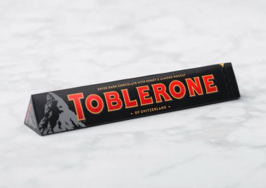 LONDON, İngiltere - 21 Ekim 2020: Beyaz mermer zemin üzerinde Ballı ve bademli fındıklı bir tüp Toblerone İsviçre koyu çikolatası.