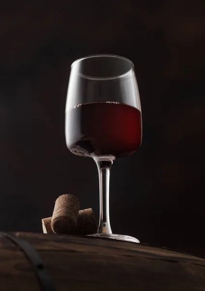 黒を基調とした木樽の上にコルクの入った赤ワインのグラス — ストック写真