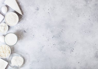 Beyaz masa arka planında taze süt ürünleri. Bir bardak süt, bir kase un, ekşi krema ve süzme peynir ve yumurta. Çelik çırpıcı