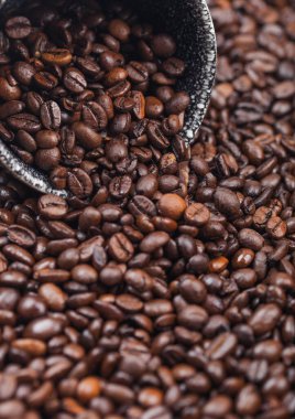 Kahve çekirdeği arka planında siyah seramik fincanda taze çiğ kahve çekirdekleri. Makro