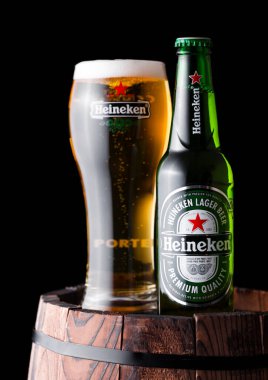 LONDON, İngiltere - 27 Nisan 2018: Eski ahşap fıçının üzerinde Heineken Lager Birası şişesi ve orijinal cam. Heineken, Heineken Enternasyonal 'ın sancak gemisi.