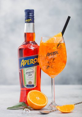 LONDON, İngiltere - 20 Mayıs 2020: Bir şişe Aperol Aperitivo yaz kokteyli orijinal cam spritz kokteyli ve portakallar ve arka planda bar kaşığı. 