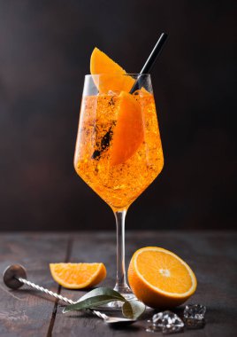 Portakal dilimli aperol spreyli yaz kokteyli ve ahşap arka planda buz küplü bar kaşığı..
