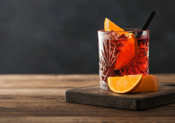 Κοκτέιλ Negroni Κρυστάλλινο Ποτήρι Πορτοκαλί Φέτα Και Μαύρο Καλαμάκι Ξύλο — Φωτογραφία Αρχείου