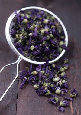 Ahşap zemin üzerinde süzgeç infüzyonunda mavi mallow çiçeği çayı. Makro