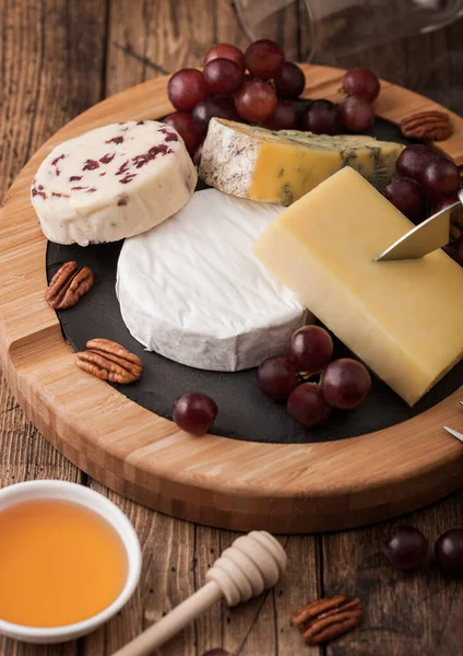 Tahtada Çeşitli Peynirler Ahşap Masa Arkasında Üzümler Mavi Stilton Kırmızı — Stok fotoğraf