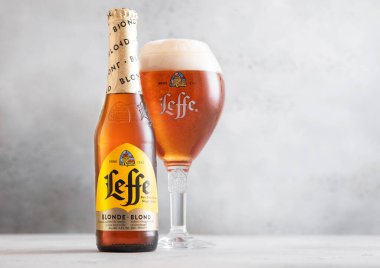 LONDON, İngiltere - 19 Temmuz 2025: Leffe Sarışın bira şişesi ve arka planda orijinal cam. 