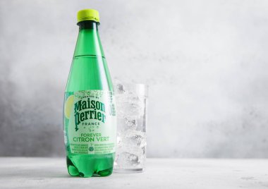 LONDON, İngiltere - 21 AĞUSTOS 2025: Bir şişe Maison Perrier Citron karbonatlı doğal maden suyu ve hafif masa üzerinde buz küpleri.
