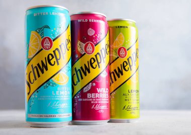 LONDON, İngiltere - 25 Temmuz 2025: Çeşitli Schweppes tonik konserveleri ve arka planda çeşitli aromalar.