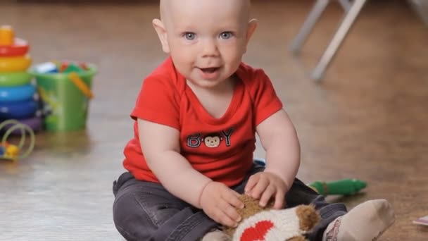 Entzückender kleiner Junge spielt mit Teddybär und lächelt. — Stockvideo