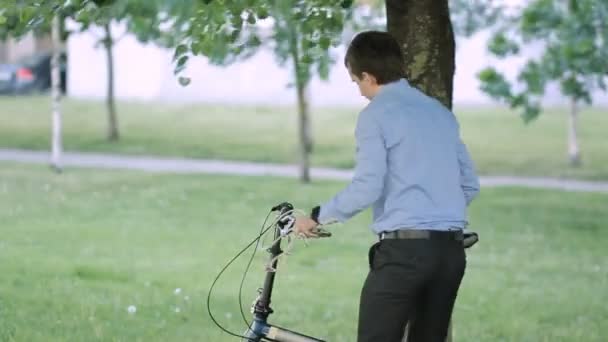 Uomo d'affari serratura bicicletta ad un albero — Video Stock