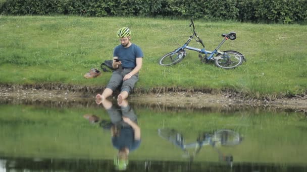 Hombre maduro feliz usando teléfono inteligente contra el lago — Vídeo de stock
