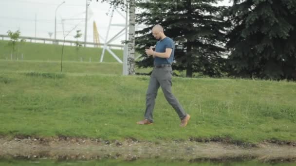 Hombre maduro feliz usando teléfono inteligente contra el lago — Vídeos de Stock