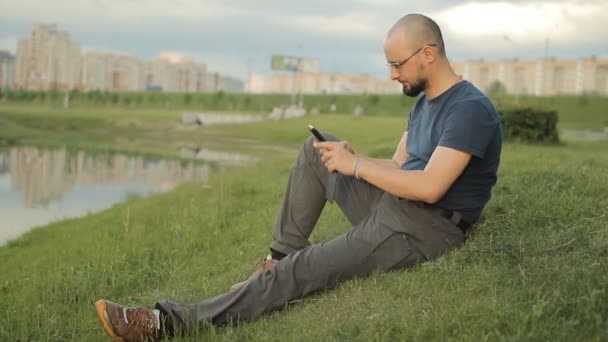 Gelukkig volwassen man met behulp van smartphone in de buurt van lake — Stockvideo