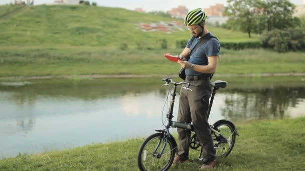 Чоловік на складному велосипеді з планшетом — стокове відео