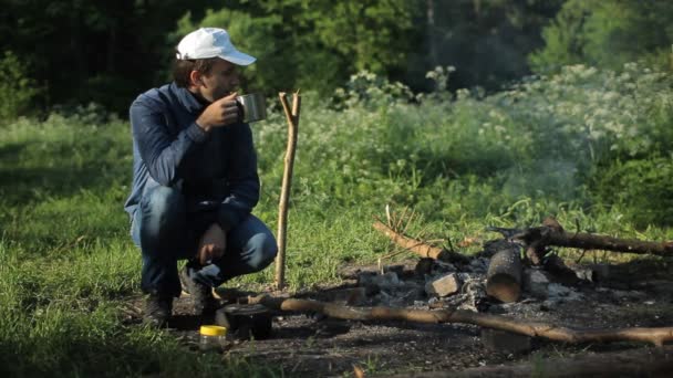 Man drankje kopje thee nea kampvuur — Stockvideo