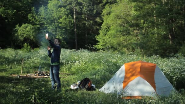 L'homme dans la forêt a perdu la connexion au téléphone. L'homme blanc ne peut pas appeler près du feu et des tentes — Video