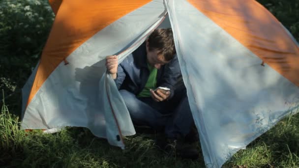 L'homme ouvre la tente et commence à parler au téléphone dans la forêt — Video