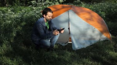 Ormanda bir çadırın yanındaki tablette adam fotoğrafları