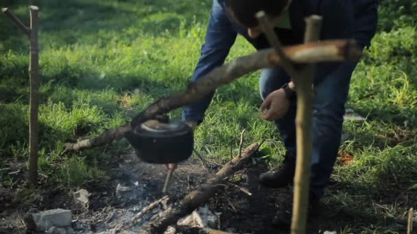 Mann wirft Holz auf dem Campingplatz ins Feuer frühmorgens im Wald — Stockvideo