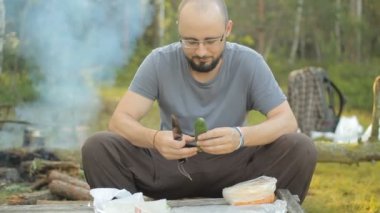 Adam salatalık kampta dilimlenmiş. Fon karşı duman yangın ve yalan turistik şeyler yayar