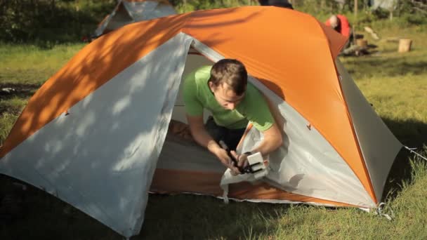 Человек делает селфи по телефону из палатки. Сначала откройте палатку, сделайте фото и закройте палатку. Солнечный день в лесу — стоковое видео
