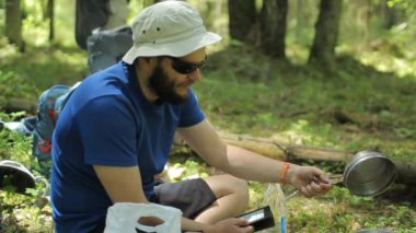 Adam ormanda bir e-kitap okur. Gaz brülöründeki turist tenceresinin yanında