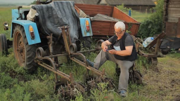 Un uomo che chiama al telefono vicino al trattore. L'agricoltura circonda — Video Stock