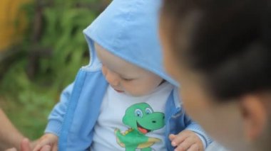 Annesinin kollarında güzel bir bebek. Dedelerin eline dokunan çocuk