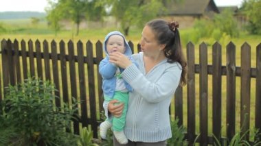 Küçük çocuk annemin ellerine bir çiçek dokunuyor. Çocuk bir yıldan az.