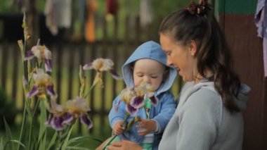 Küçük çocuk annemin ellerine bir çiçek dokunuyor. Çocuk bir yıldan az.