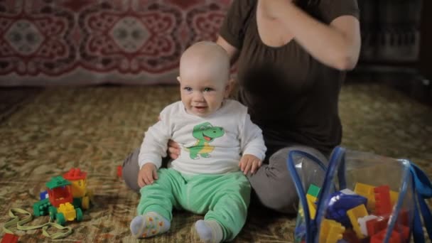 엄마와 미소와 함께 집에서 장난감을 가지고 노는 아름다운 아기. 소년은 1 년 미만입니다. — 비디오