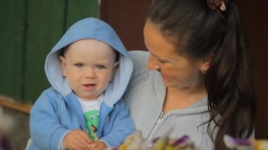 Küçük çocuk annemin ellerine bir çiçek dokunuyor. Çocuk bir yıldan az.