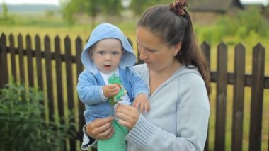 Küçük çocuk anne ellerine oturan bir çiçek düşürür. Çocuk bir yıldan az.