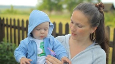 Küçük çocuk annemin ellerine bir çiçek dokunuyor. Çocuk bir yıldan az.