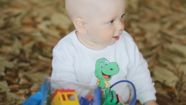 Το μωρό παίζει στο σπίτι στο πάτωμα με παιχνίδια. Όμορφο αγόρι λιγότερο από ένα χρόνο — Αρχείο Βίντεο