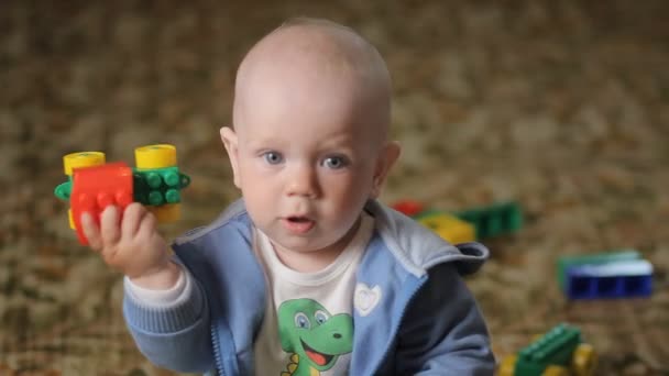 Bebé jugando en casa en el suelo con juguetes. Chico guapo menos de un año — Vídeos de Stock