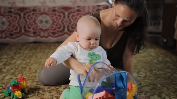 Mooie baby spelen met speelgoed met zijn moeder thuis. De jongen is minder dan een jaar — Stockvideo