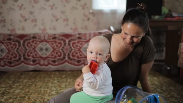 Hermoso bebé jugando con juguetes en casa con mamá y sonrisas. El chico tiene menos de un año. — Vídeo de stock