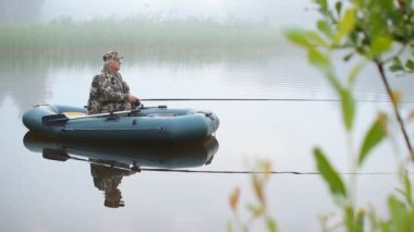 Bir tekne olta balık için bekleyen ile bir balıkçı. Erken sabah sis göl