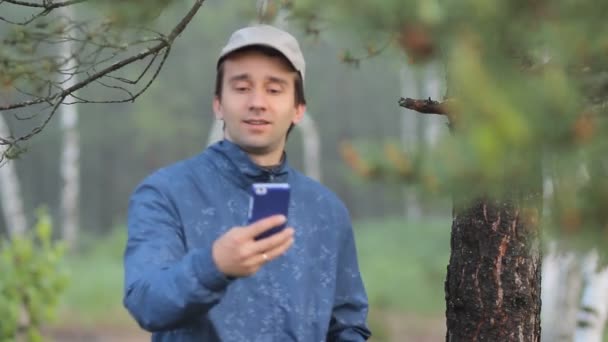 L'homme fait la photo au téléphone près d'un arbre dans la forêt. Tôt le matin 
