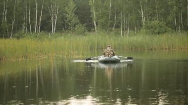 Adam balıkçı bir şişme bot bir gölde yüzer. Sabah erken